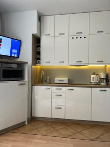 a kitchen with white cabinets and a flat screen tv at Apartament Przy Kawczej in Międzyzdroje