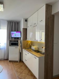 a kitchen with white cabinets and a tv on the wall at Apartament Przy Kawczej in Międzyzdroje
