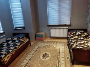 two beds in a room with a rug and two windows at Goradil Beach in Baku
