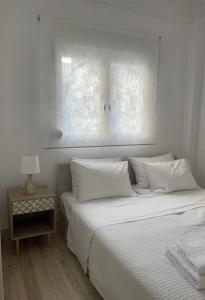 a white bed with white pillows and a side table at Le Plaza in Thessaloniki