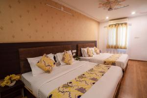 a hotel room with two beds and a window at Tripli Hotels Arunoday Palace in Udaipur