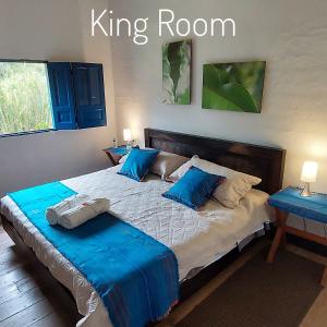a bedroom with a king bed with blue pillows at Reserva Guadalajara - Cocora Valley in Salento