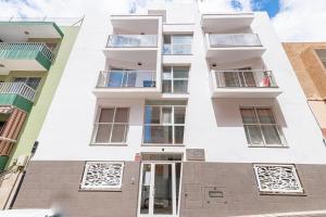um edifício de apartamentos com paredes e janelas brancas em Edf BRISA en El Médano em El Médano