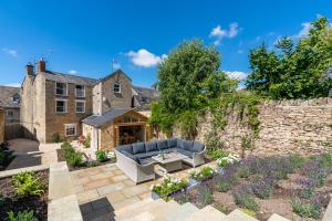 a garden with a blue couch in front of a stone wall at Merchant House in Charlbury