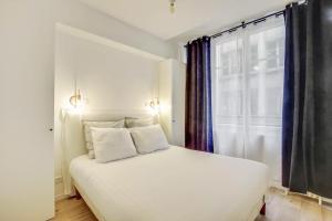 a white bed in a room with a window at Central & Stylish renovated Parisian apt / 6-8 guests in Paris