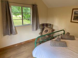 a bedroom with a bed with a window and a chair at Orchard Cabin Herefordshire Wye Valley in Ross on Wye