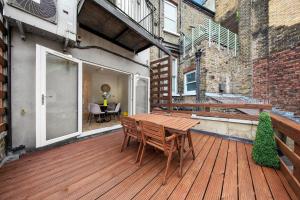 una terraza de madera con mesa y sillas. en Roof terrace 2BED Property CAMDEN free WiFi en Londres