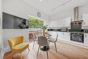 cocina con armarios blancos, mesa y sillas en Roof terrace 2BED Property CAMDEN free WiFi en Londres