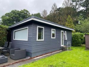 a black tiny house in a yard at Mooi verblijf op rustig park in Ermelo