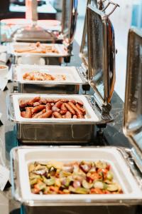 a buffet line with trays of food on a table at Resort Dlouhé Stráně in Loučná nad Desnou