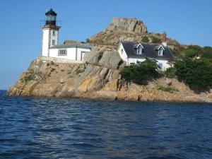 a lighthouse on a rocky island in the water at The Originals Boutique, Hôtel de La Baie de Morlaix in Carantec