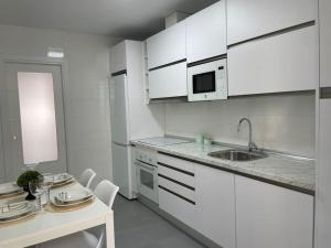 a kitchen with white cabinets and a sink and a table at piso recinto ferial en teatinos in Málaga