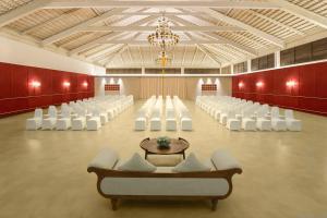 a banquet hall with white chairs and a chandelier at Aurika, Coorg - Luxury by Lemon Tree Hotels in Madikeri