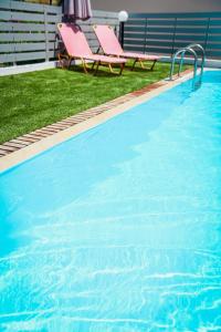 a swimming pool with two pink chairs next to it at Grace Studios & Apartments in Sfakaki