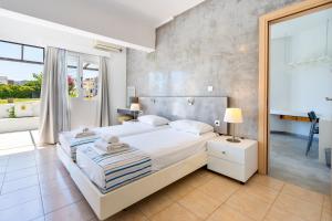 um quarto com uma cama branca e uma grande janela em Mando Living -Faliraki em Faliraki