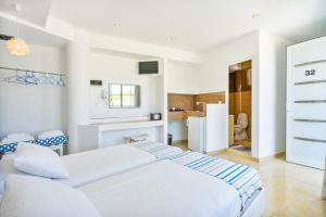 a white bedroom with two beds and a refrigerator at Mando Living -Faliraki in Faliraki