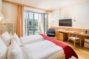 a hotel room with a bed and a desk and a television at Seehotel Rheinsberg in Rheinsberg