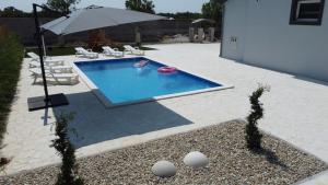 a person in a swimming pool with an umbrella at Villa Heaven in Zemuniki