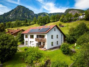 ein weißes Haus auf einem Hügel mit Bergen im Hintergrund in der Unterkunft Alpenraum in Bad Hindelang