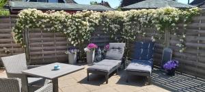 a patio with two chairs and a table and flowers at Huus Utspann in Tönning