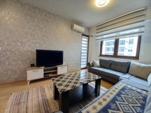 a living room with a couch and a flat screen tv at Grand Prestij Excellent Apartman in Skopje
