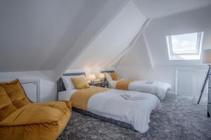 a attic bedroom with two beds and a chair at Gwynne House - 6 Bed Holiday Home - Tenby Harbour in Tenby