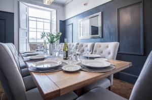 a dining room with a wooden table and chairs at Gwynne House - 6 Bed Holiday Home - Tenby Harbour in Tenby