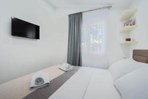 ein weißes Schlafzimmer mit einem Bett und einem TV in der Unterkunft Villa Marijo in Ražanj