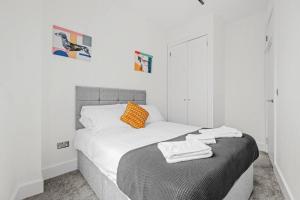 1 dormitorio con cama con sábanas blancas y almohada naranja en Charming 2 bed apartment Free WiFi close to Camden en Londres