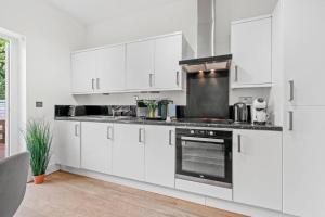 una cocina con armarios blancos y horno negro en Charming 2 bed apartment Free WiFi close to Camden en Londres