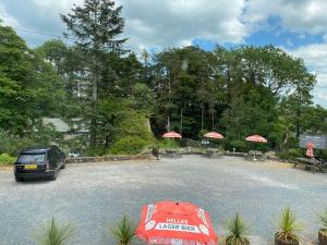 ein Auto auf einem Parkplatz mit Tischen und Sonnenschirmen geparkt in der Unterkunft The Mill Inn in Penrith