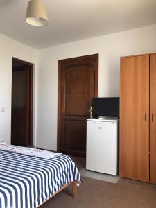 a bedroom with a bed and a refrigerator and a door at Vila ALBA AREAL in Costinesti
