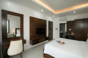 a bedroom with a white bed and a mirror at DAD Resort Phú Quốc in Phú Quốc