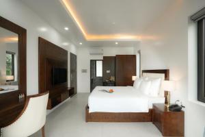 a bedroom with a white bed and a television at DAD Resort Phú Quốc in Phú Quốc