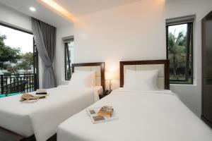 two beds in a room with two windows at DAD Resort Phú Quốc in Phú Quốc