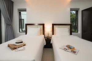 two beds in a room with a hat and magazines at DAD Resort Phú Quốc in Phú Quốc
