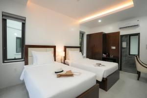 two beds in a hotel room with a hat on top at DAD Resort Phú Quốc in Phú Quốc