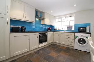 a kitchen with white cabinets and a washer and dryer at Sea la Vie in Newcastle