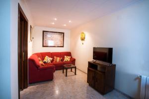 a living room with a red couch and a tv at Rosabelas in Alcanar