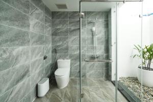 a bathroom with a toilet and a glass shower at DAD Resort Phú Quốc in Phú Quốc