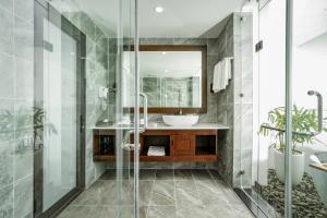 a bathroom with a sink and a glass shower at DAD Resort Phú Quốc in Phú Quốc