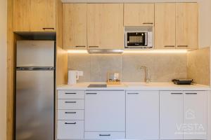 a kitchen with white cabinets and a stainless steel refrigerator at De Mar Village Apartments, Agios Nikolaos in Ayios Nikolaos Sithonia