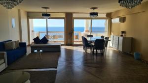 uma sala de estar com um sofá azul e uma mesa com cadeiras em Midpoint Sea View - families only em Alexandria