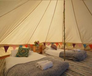 two beds in a tent with towels on them at Starlight Glamping 