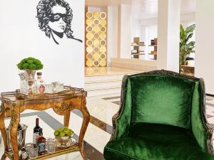 einem grünen Stuhl neben einem Tisch mit Weinflaschen in der Unterkunft Grecotel Pallas Athena in Athen