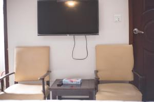 2 sillas en una habitación con TV en la pared en GOHO Rooms Badar, en Karachi