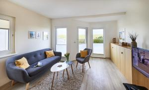 sala de estar con sofá azul y TV en Haus Pamir _ Fewo 20 en Cuxhaven