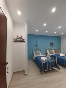 a bedroom with two beds and a blue wall at Elipa in Mandra Capreria