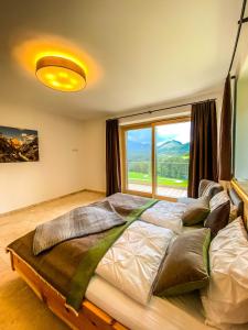 ein großes Bett in einem Zimmer mit einem großen Fenster in der Unterkunft Ferienvilla Joachimsberg mit Swimspa und Sauna in Wienerbruck