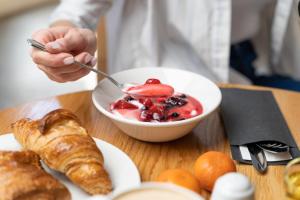 a person eating a bowl of fruit and croissants on a table at Holiday Inn Express Aberdeen City Centre, an IHG Hotel in Aberdeen